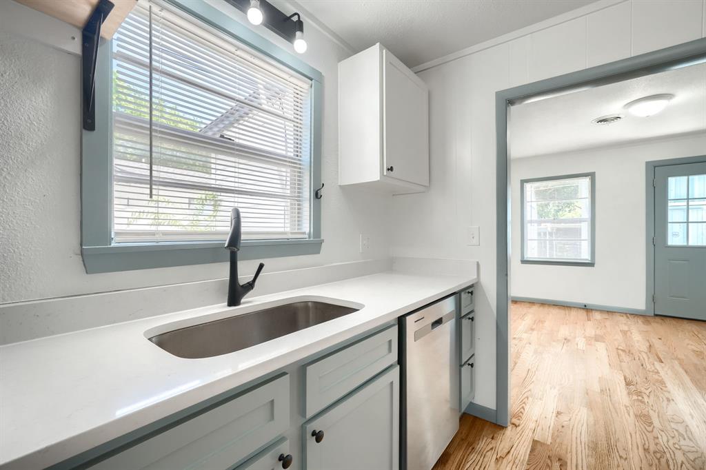 1802 Refinery Road Gainesville, TX 76240 - Photo 9 of 27 Kitchen sink area featuring light-toned cabinetry, light countertops, a stainless steel sink, and a black gooseneck faucet