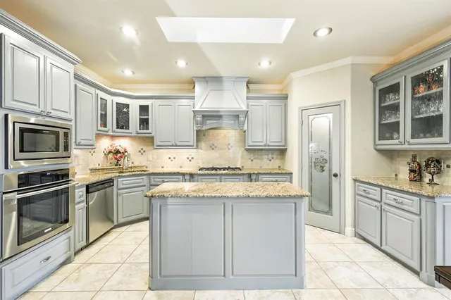a kitchen with stainless steel appliances granite countertop a stove top oven a sink dishwasher a refrigerator and white cabinets with wooden floor