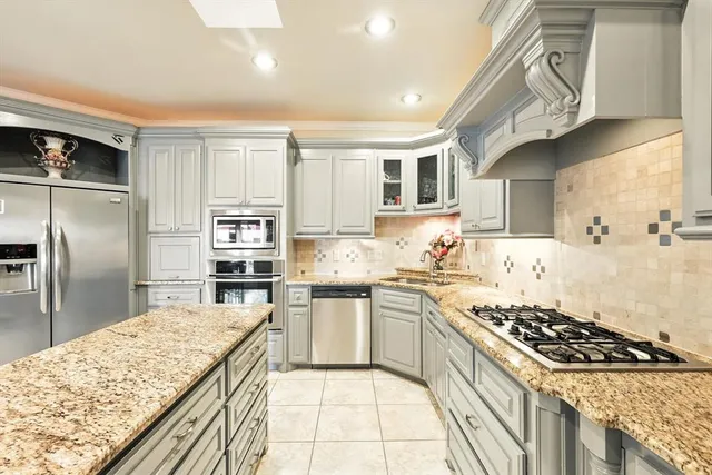 a kitchen with stainless steel appliances granite countertop a sink stove refrigerator and cabinets