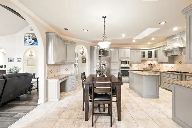 a kitchen with stainless steel appliances kitchen island granite countertop a table chairs sink and cabinets