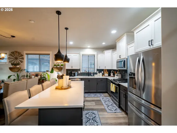 a kitchen with stainless steel appliances kitchen island granite countertop a refrigerator a stove a sink dishwasher with a dining table and chairs