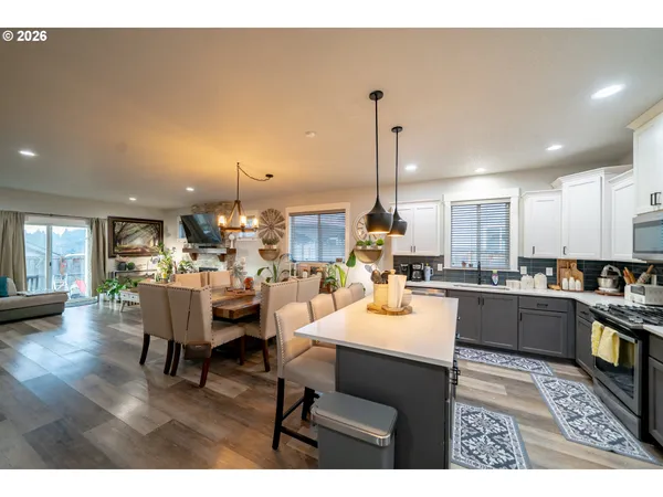 a kitchen with stainless steel appliances kitchen island granite countertop a table chairs and a view of living room