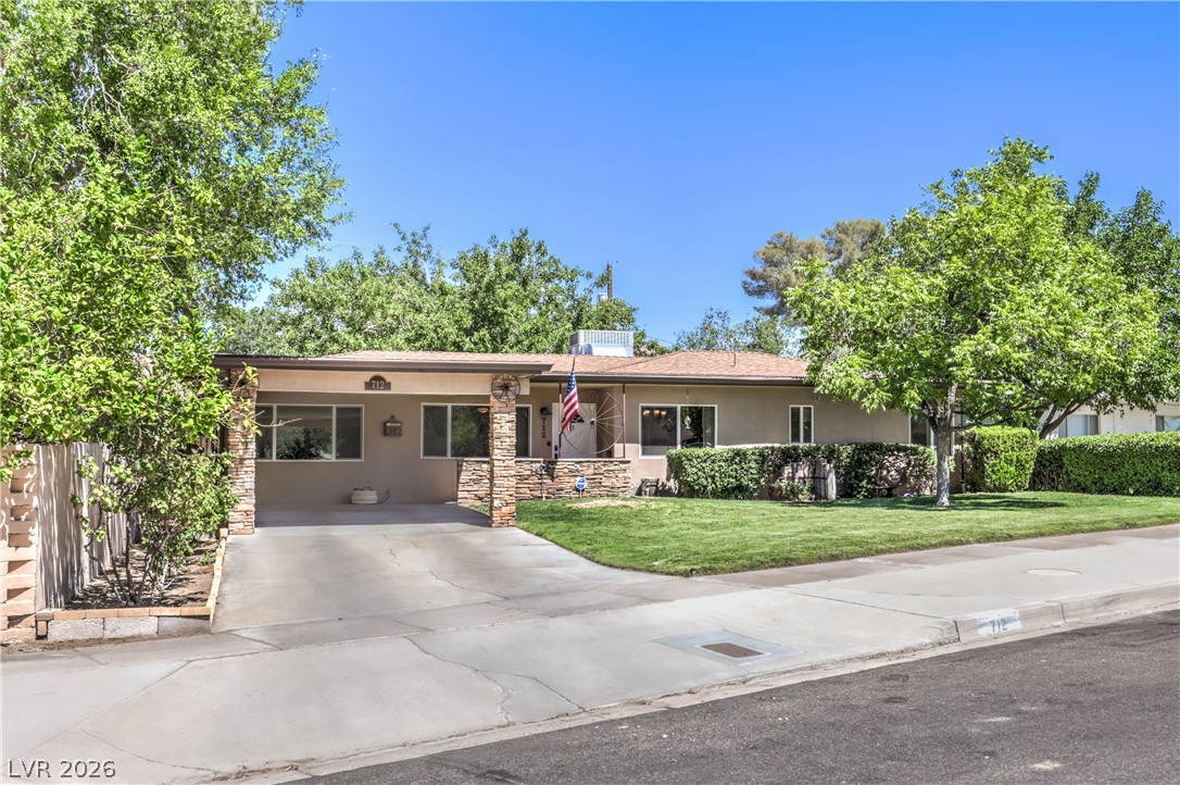 Mature trees and neat landscaping frame this welcoming single-story residence with a paved driveway.