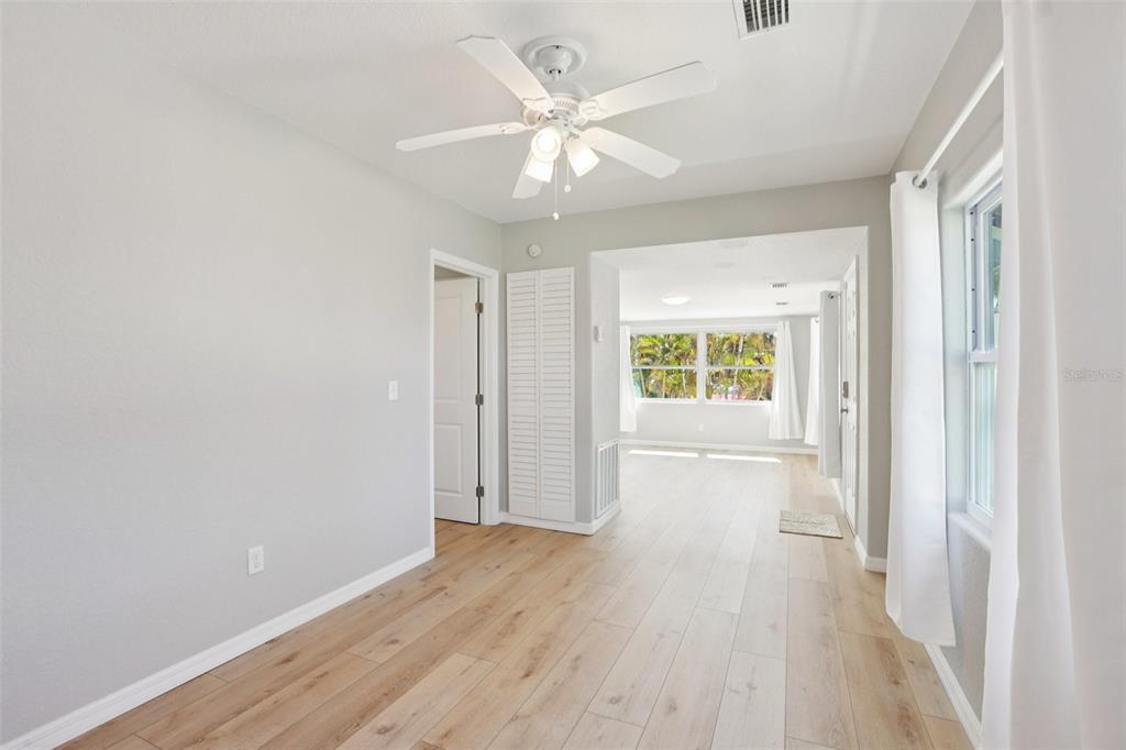 13135 4th Street East Madeira Beach, FL 33708 - Photo 11 of 24 an empty room with wooden floor chandelier fan and windows