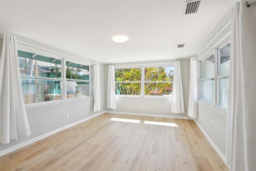 13135 4th Street East Madeira Beach, FL 33708 - Photo 4 of 24 an empty room with wooden floor and windows