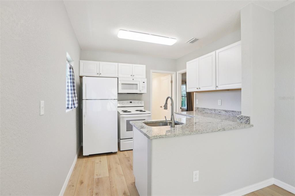 13135 4th Street East Madeira Beach, FL 33708 - Photo 7 of 24 a kitchen with stainless steel appliances granite countertop a refrigerator sink and stove
