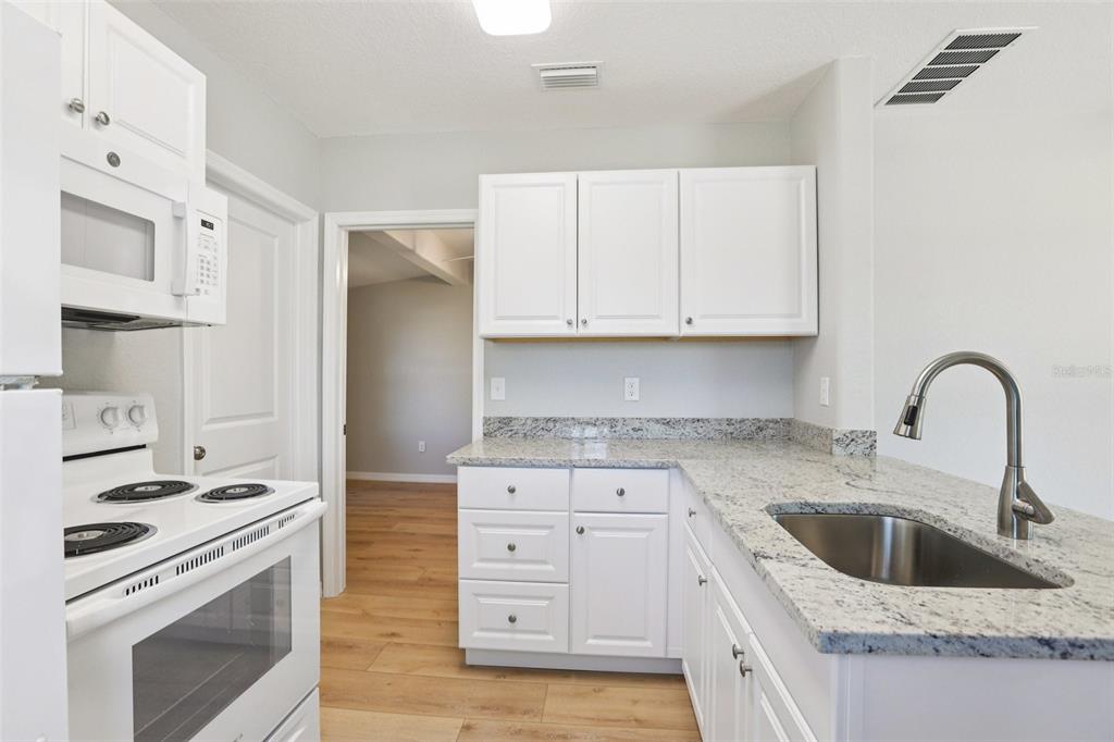 13135 4th Street East Madeira Beach, FL 33708 - Photo 8 of 24 a kitchen with granite countertop white cabinets and white appliances