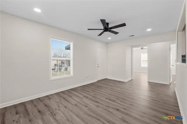 a view of empty room with wooden floor and window