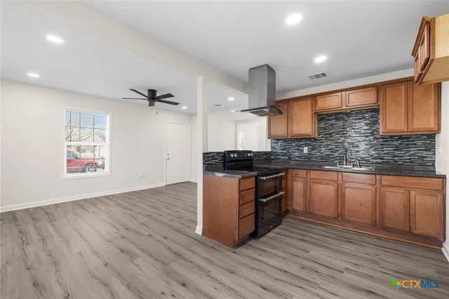 a kitchen with granite countertop wooden floors appliances and cabinets