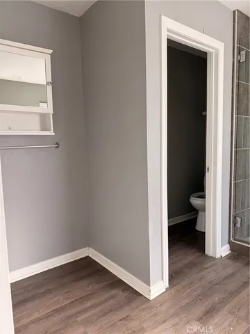 a view of a hallway with wooden floor and a bathroom