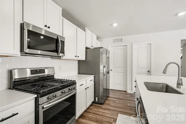a kitchen with stainless steel appliances a stove a sink a microwave and cabinets