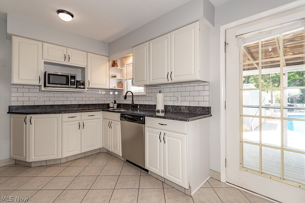 1314 Mayfield Ridge Road Cleveland, OH 44124 - Photo 10 of 40 Kitchen featuring white cabinetry, stainless steel appliances, decorative backsplash, sink, and light tile patterned floors
