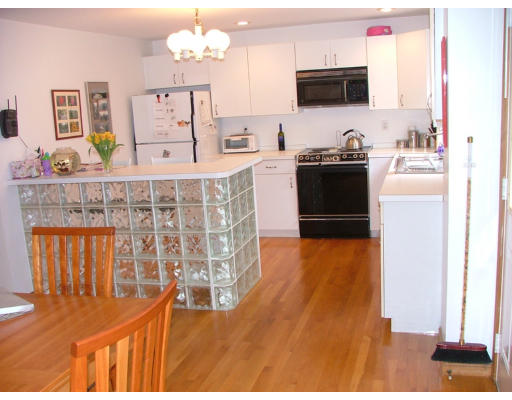 10 Cozy Street, Unit 10 Watertown, MA 02472 - Photo 5 of 11 a kitchen with stainless steel appliances kitchen island granite countertop a stove a sink and a microwave