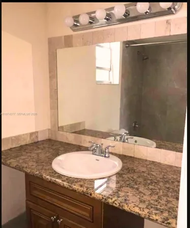 a bathroom with a granite countertop sink and a mirror