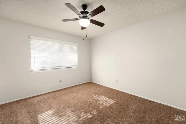 an empty room with a window and a fan