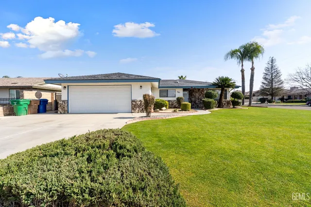 a front view of a house with garden and trees