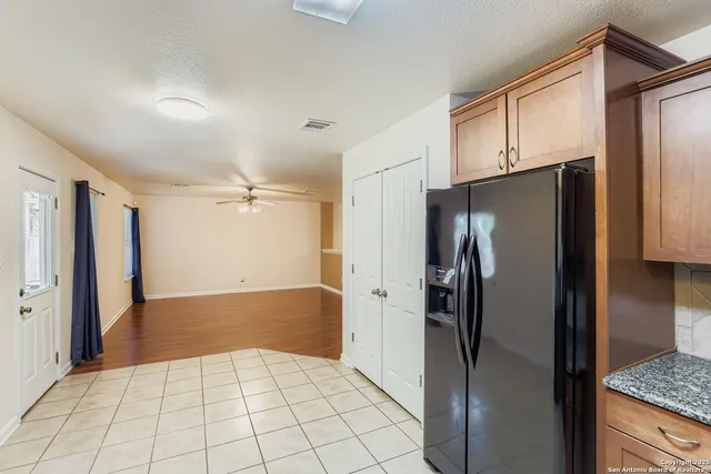 a view of a refrigerator in kitchen and an empty room in wooden floor