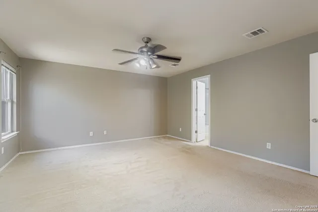 an empty room with chandelier fan and windows