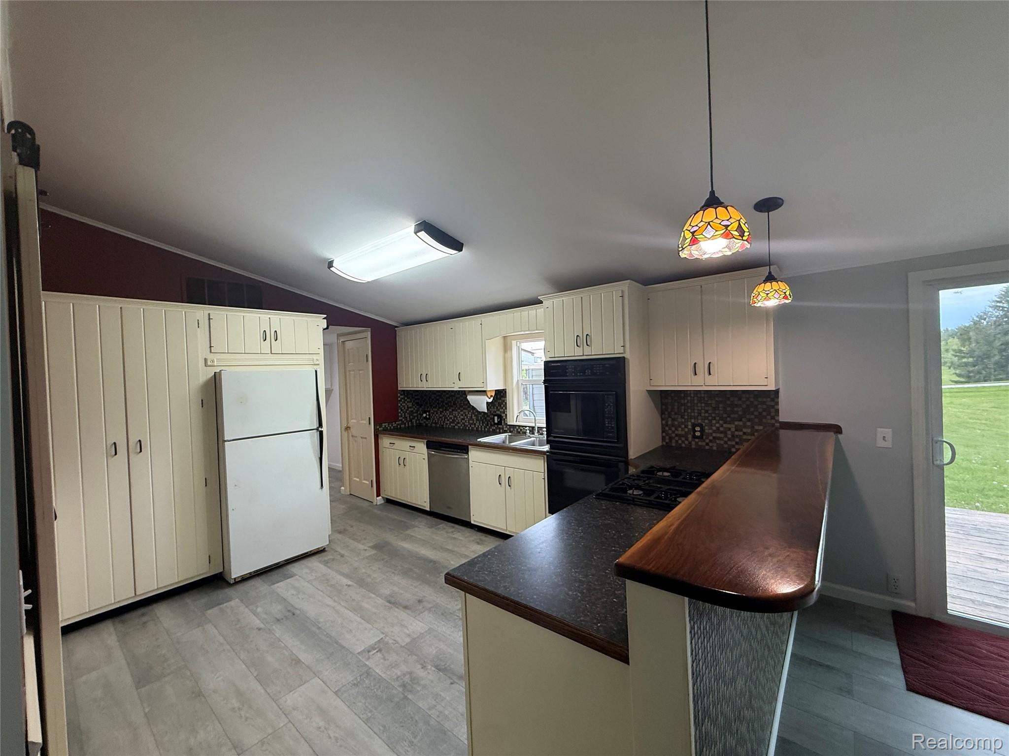 7149-7163 Burpee Road Grand Blanc, MI 48439 - Photo 44 of 72 Kitchen with dark countertops, a peninsula, black appliances, lofted ceiling, and tasteful backsplash