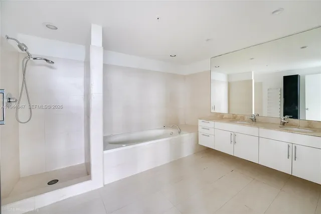 a bathroom with a bathtub a double vanity sink and mirror