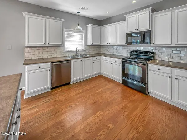 a kitchen with stainless steel appliances granite countertop a sink a stove top oven a counter space and cabinets