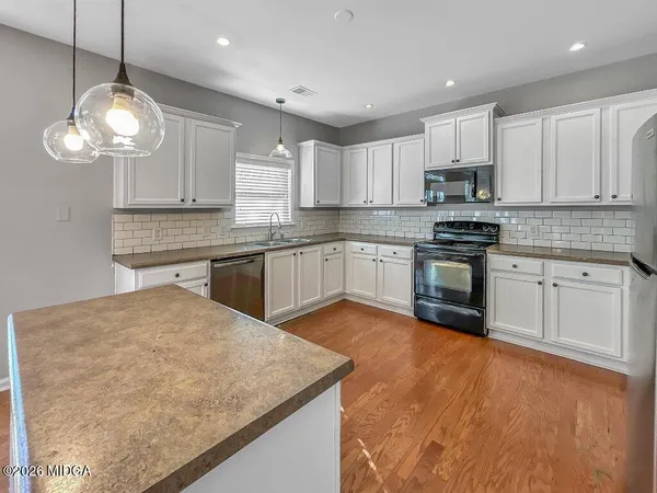a kitchen with stainless steel appliances granite countertop a sink a stove and a wooden floors
