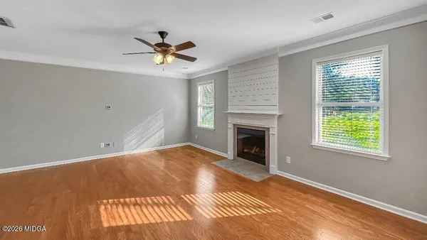 a view of a livingroom with a fireplace a ceiling fan and wooden floor