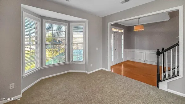 a view of empty room with wooden floor and fan