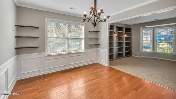 a view of a hallway with wooden floor and chandelier
