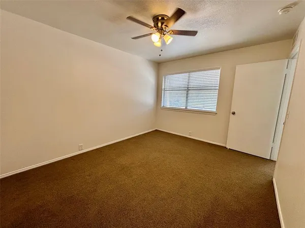 an empty room with a window and a fan
