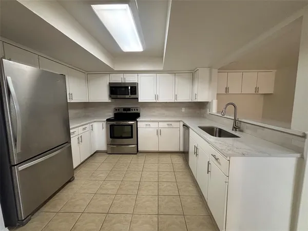 a kitchen with granite countertop a sink a counter top space stainless steel appliances and cabinets