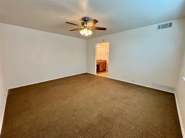 a view of an empty room with a chandelier fan