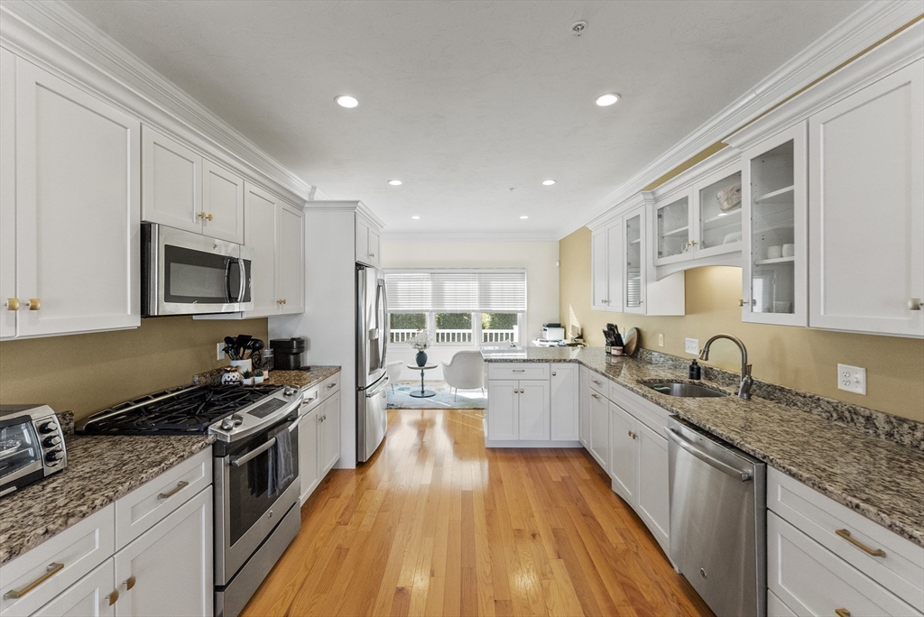 60 Robbins Road, Unit 25 Plymouth, MA 02360 - Photo 29 of 42 a large kitchen with stainless steel appliances granite countertop a stove a sink dishwasher and a microwave oven with white cabinets