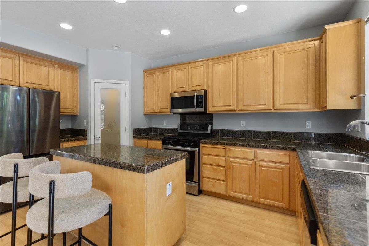 a kitchen with stainless steel appliances granite countertop a stove a sink a microwave a refrigerator and white cabinets