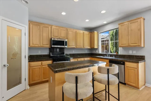 a kitchen with granite countertop a stove a sink a microwave a dining table and chairs