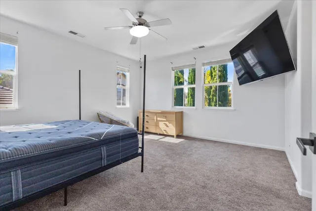 a bedroom with a bed a flat screen tv and a window