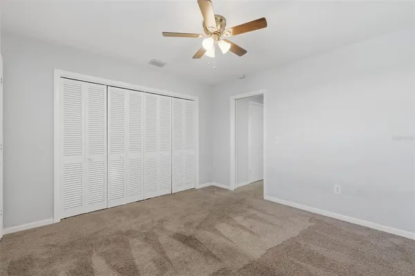 an empty room with a chandelier fan and windows