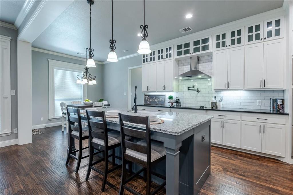 104 Lagrange Court Weatherford, TX 76088 - Photo 6 of 25 a kitchen with stainless steel appliances kitchen island a table chairs in it and wooden floors