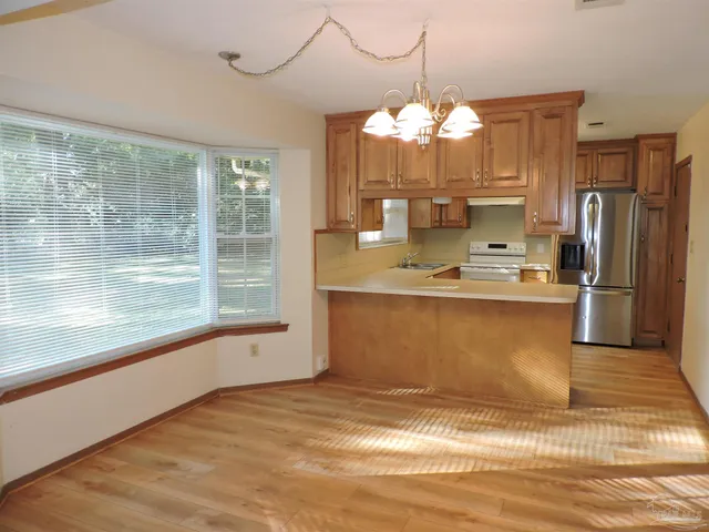 a view of kitchen with granite countertop sink and dishwasher a refrigerator with wooden floor