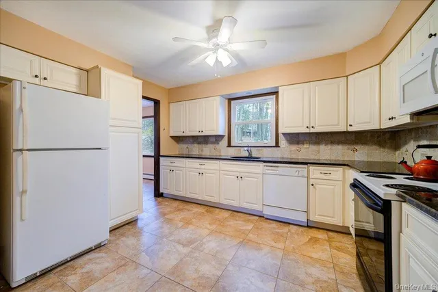 a kitchen with stainless steel appliances granite countertop a refrigerator a sink dishwasher a stove top oven a refrigerator and white cabinets