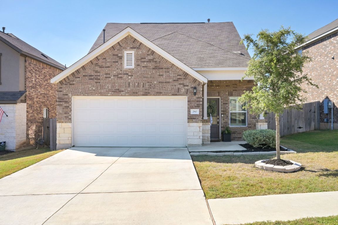 280 Pepperbark Loop Buda, TX 78610 - Photo 2 of 38 Traditional-style house featuring driveway, brick siding, an attached garage, roof with shingles, and a porch
