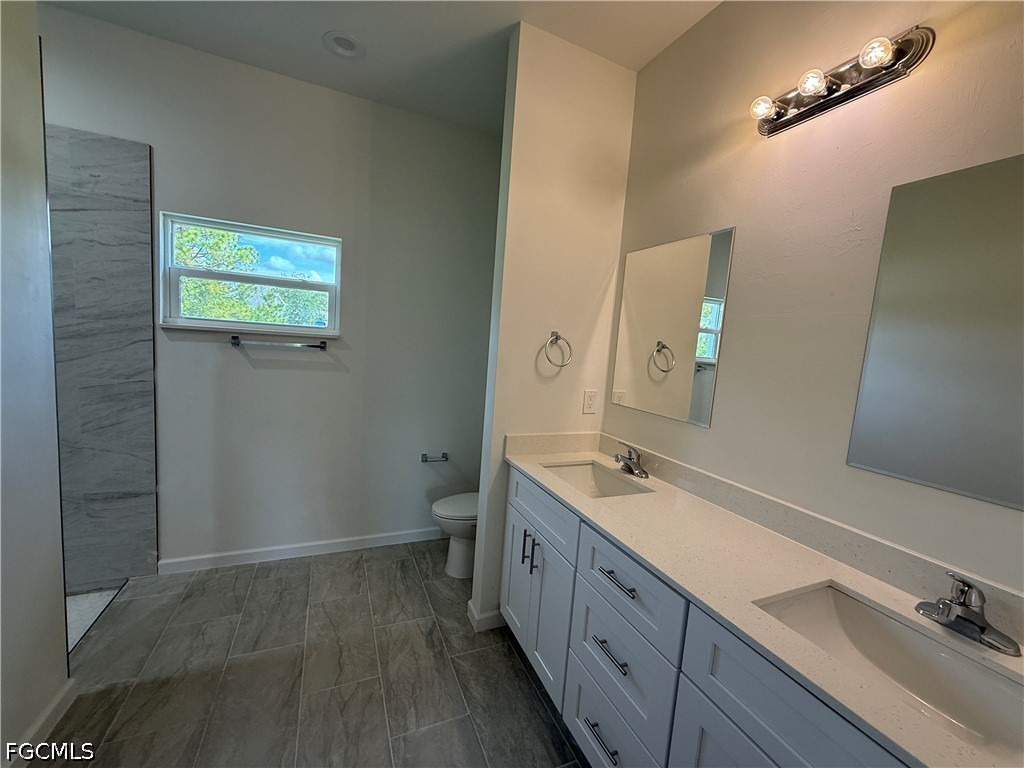 2809 Darlene Place Lehigh Acres, FL 33971 - Photo 12 of 26 a spacious bathroom with a double vanity sink a toilet and a mirror