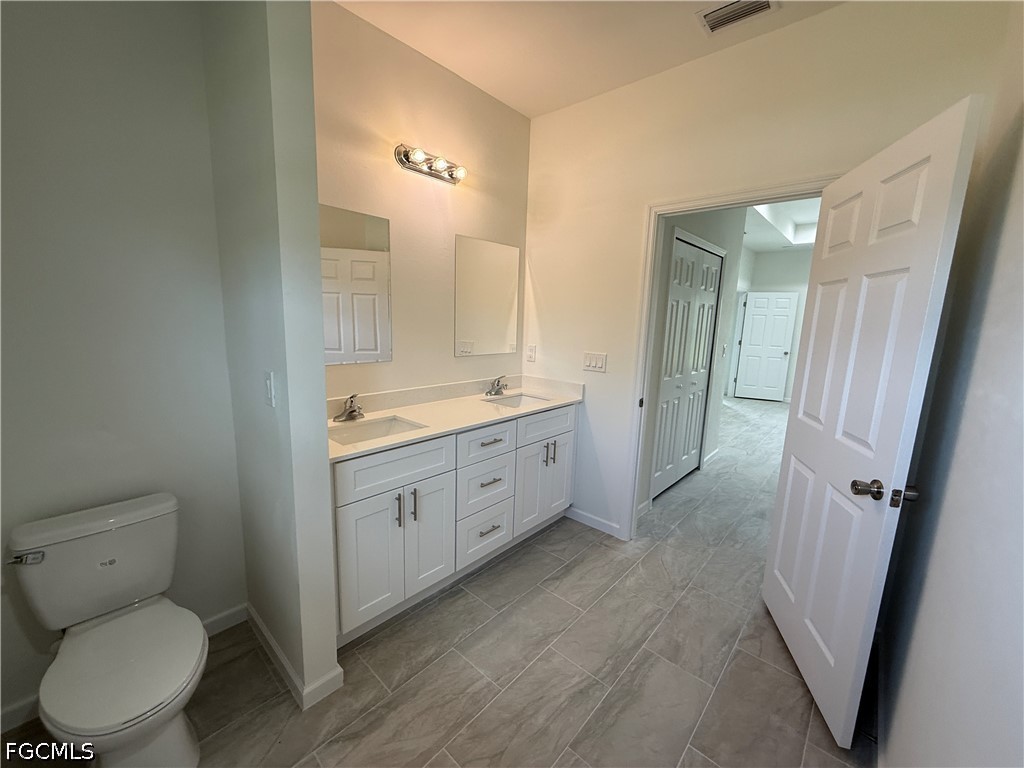 2809 Darlene Place Lehigh Acres, FL 33971 - Photo 13 of 26 a spacious bathroom with a double vanity sink toilet and shower