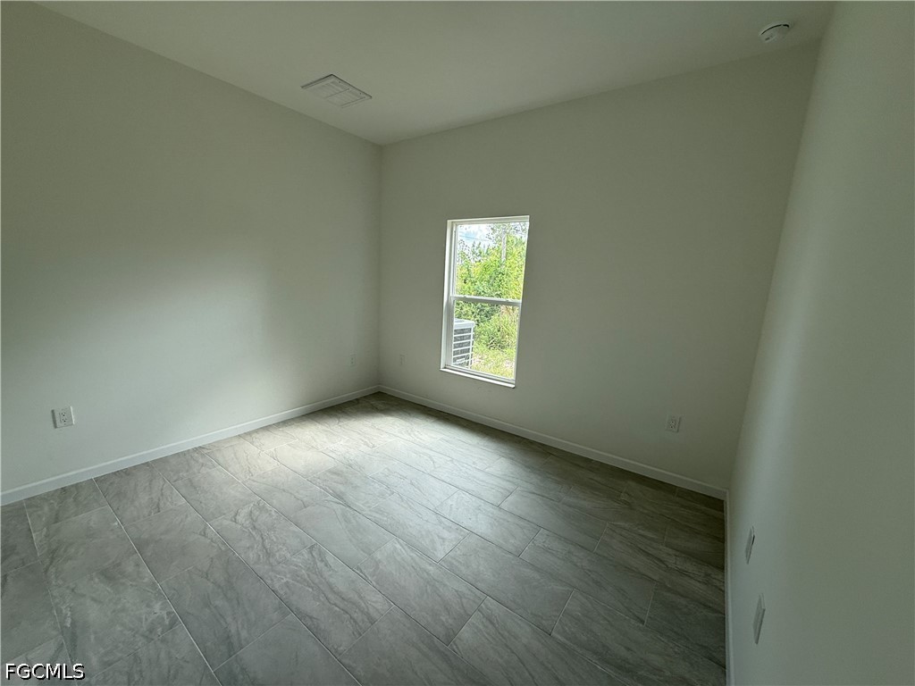 2809 Darlene Place Lehigh Acres, FL 33971 - Photo 18 of 26 an empty room with wooden floor and windows