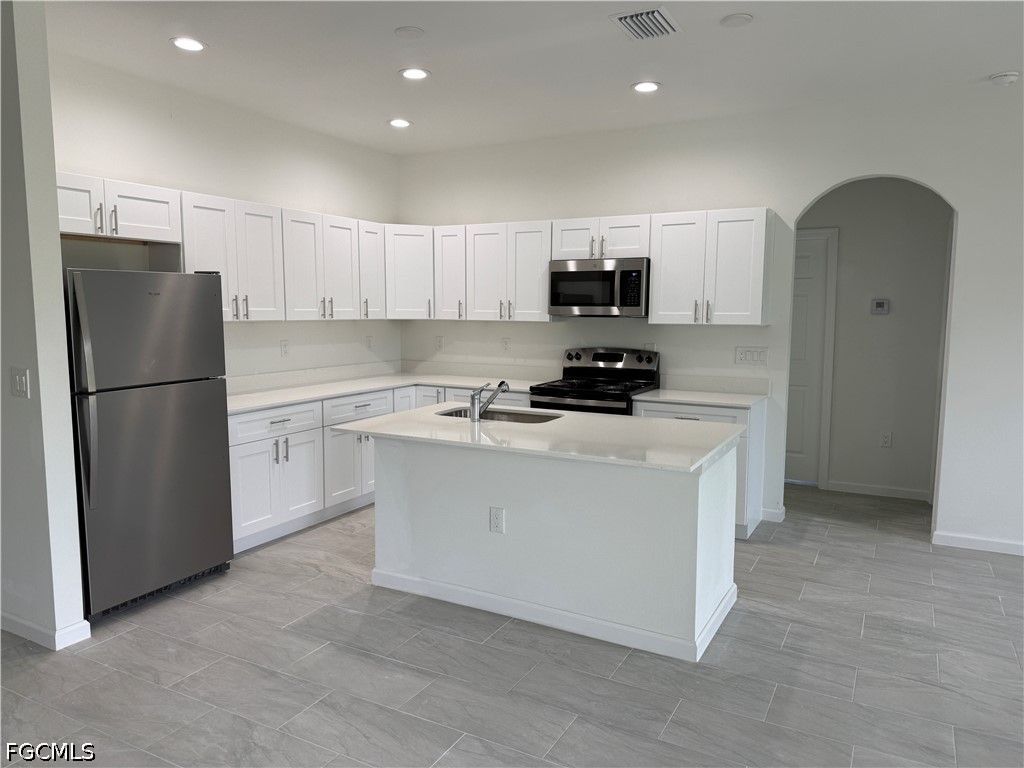 2809 Darlene Place Lehigh Acres, FL 33971 - Photo 4 of 26 a kitchen with stainless steel appliances a refrigerator sink and white cabinets