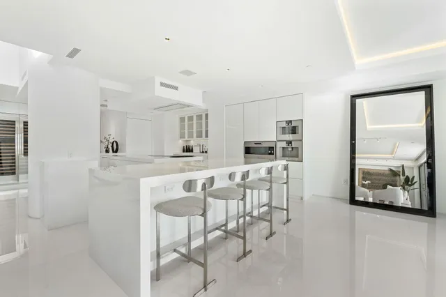 a kitchen with stainless steel appliances kitchen island granite countertop a dining table chairs and a refrigerator