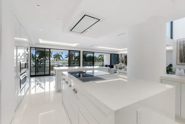 a large white kitchen with a large window and stainless steel appliances