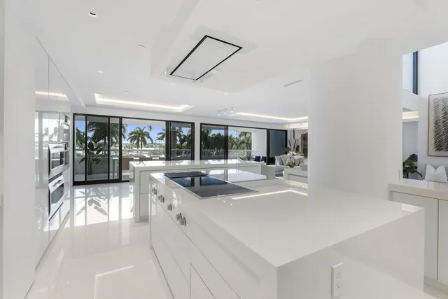 a large white kitchen with a large window and stainless steel appliances