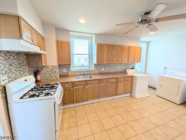 a kitchen with a stove a sink cabinets and a window