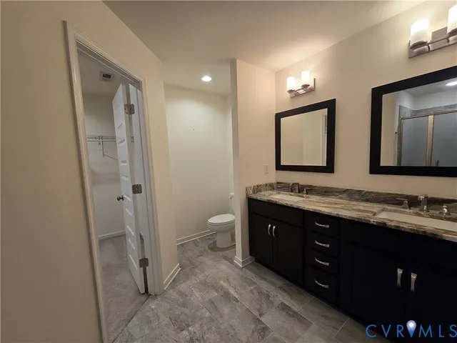 a bathroom with a double vanity sink and mirror with toilet